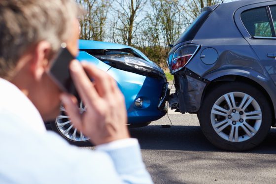 Hombre en un choque hablando por teléfono para reclamar a un seguro de coche