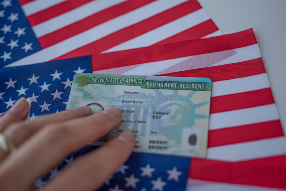 Mano humana sobre una green card americana tras un ajuste de estatus en Estados Unidos
