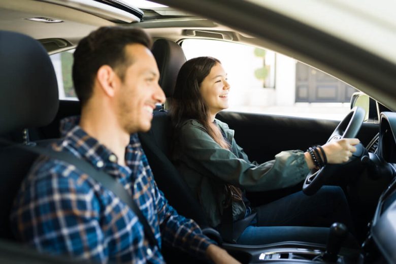 Padre e hija conduciendo un auto - Como transferir la propiedad de un auto a un familiar en California - Cost-U-Less